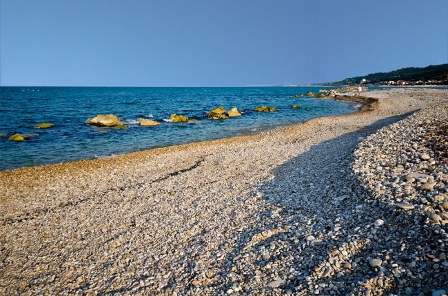 Spiaggia di ciottoli e mare con rocce.