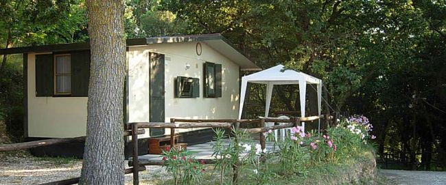 Una casetta prefabbricata con gazebo e fiori davanti.