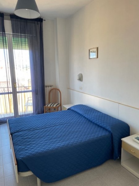 Camera con letto matrimoniale blu e balcone.