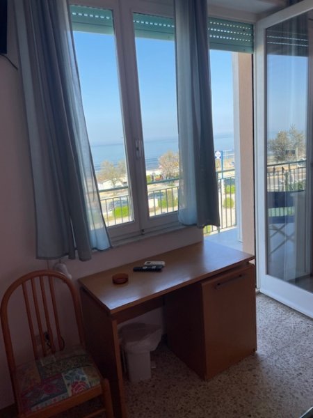 Vista mare da finestra con scrivania e sedia.