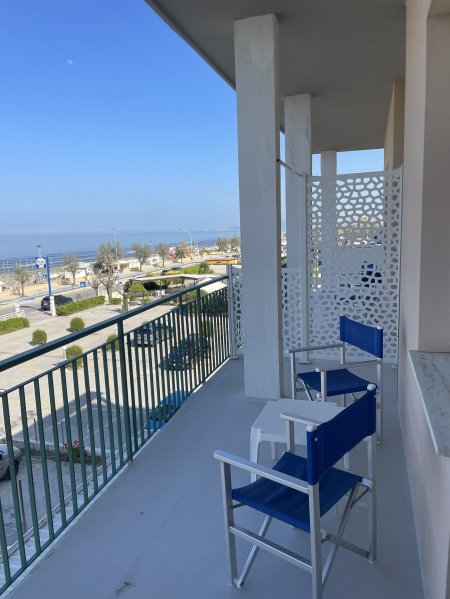 Balcone con sedie blu e vista sul mare.