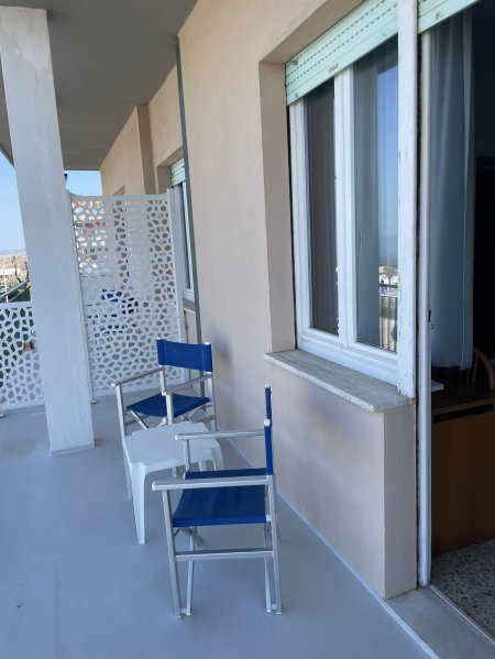 Balcone con sedie blu e grata decorativa.