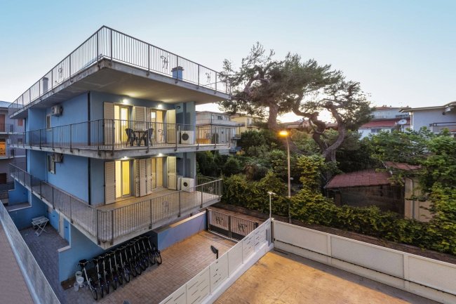 Edificio blu a tre piani con balconi e biciclette.