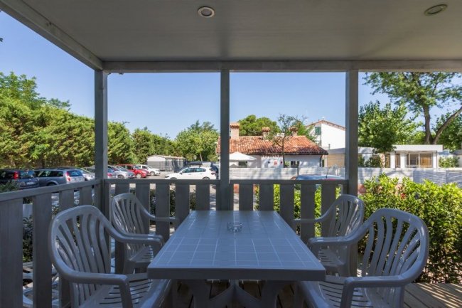 Tavolo esterno con sedie di plastica su veranda coperta.