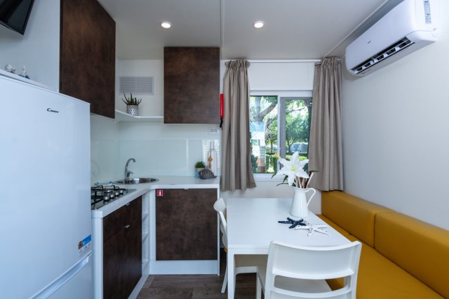 Cucina moderna con tavolo bianco e divano giallo.