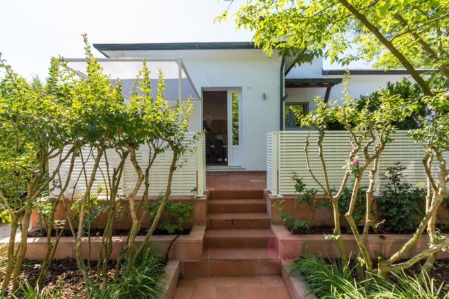 Ingresso di una casa con gradini e piante laterali.
