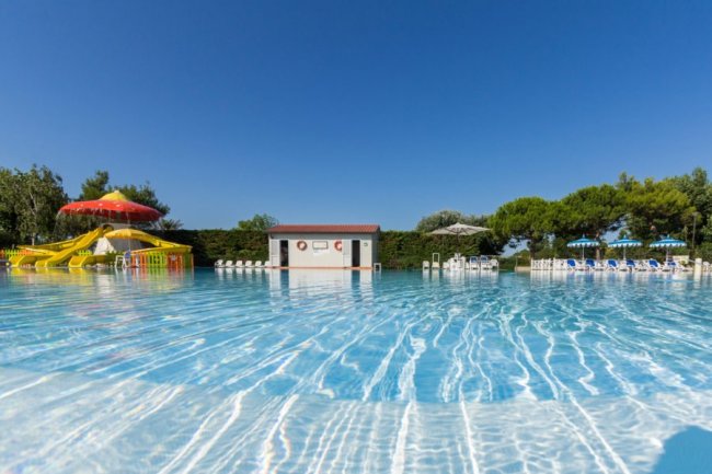 Piscina all'aperto con scivoli e ombrelloni.