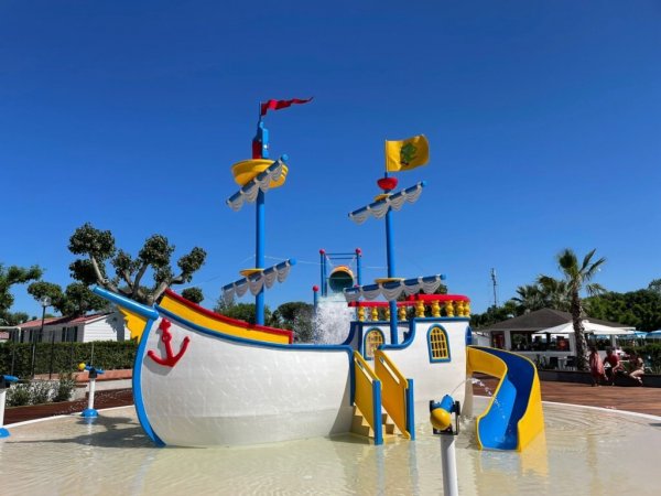 Nave giocattolo colorata con scivoli in una piscina bassa.