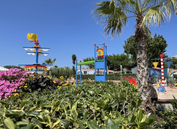 Area giochi acquatica con piante e decorazioni colorate.