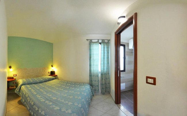 Camera da letto con letto matrimoniale e porta del bagno.