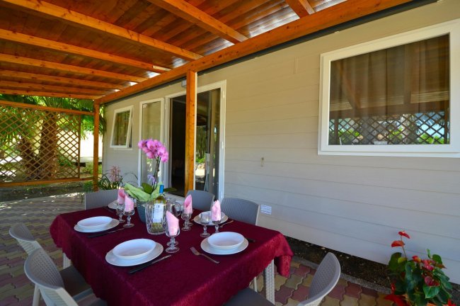 Veranda con tavolo apparecchiato e copertura in legno.