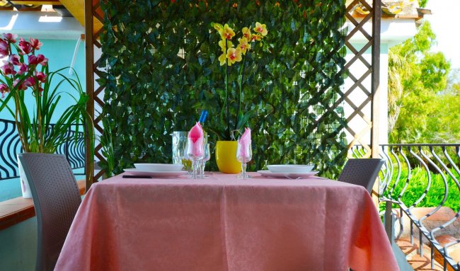Tavolo con tovaglia rosa e decorazioni floreali.