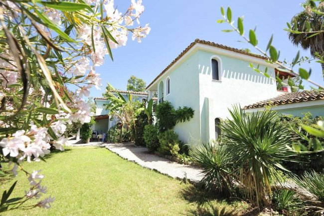 Casa azzurra con giardino e vegetazione.