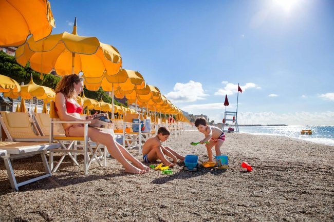 Spiaggia con ombrelloni gialli e bambini che giocano.