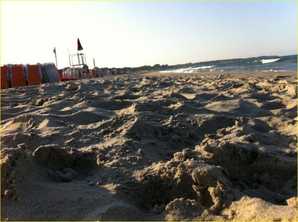 Primo piano di sabbia su una spiaggia, mare all'orizzonte.