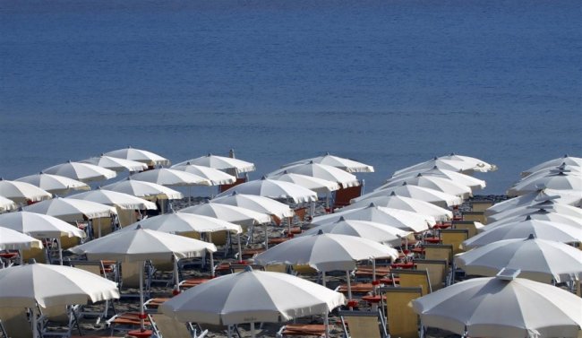 Spiaggia con file di ombrelloni bianchi.