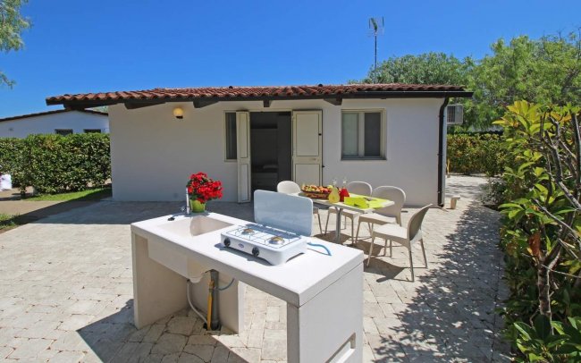 Casa bianca con patio, tavolo apparecchiato e fornello.