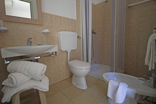 Bagno con doccia, WC, bidet e lavabo con asciugamani.