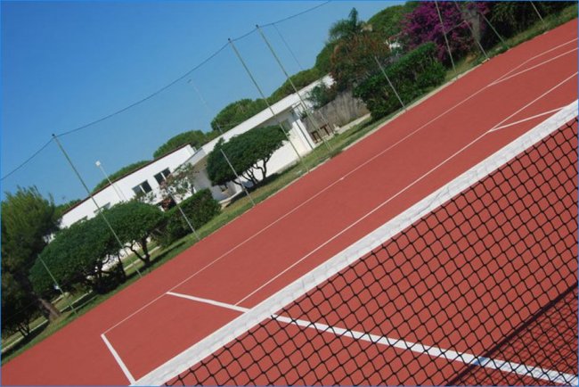 Campo da tennis con rete in primo piano.