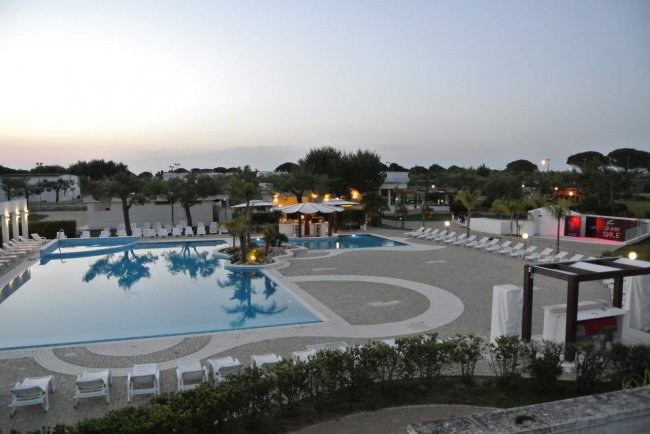 Ampia piscina con lettini bianchi.