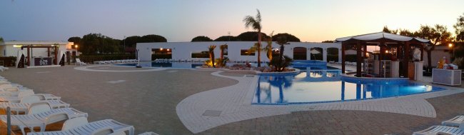 Ampio patio con piscina e lettini, al tramonto.