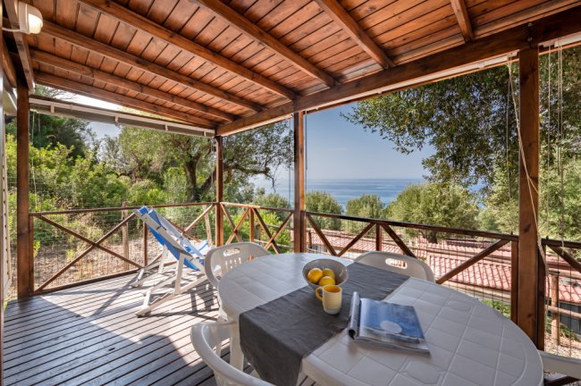 Terrazza coperta con tavolo, sedie e vista mare.