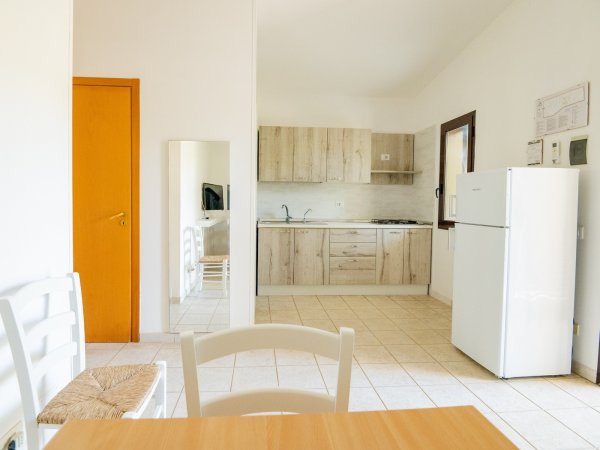 Cucina minimalista con mobili in legno e frigo bianco.