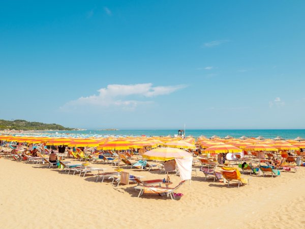 Spiaggia con ombrelloni gialli e arancioni.