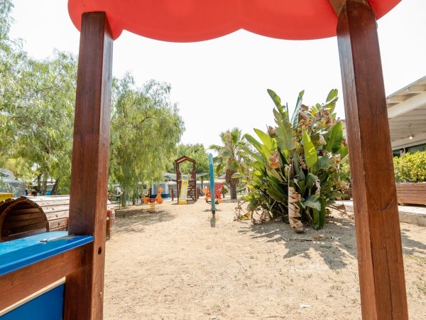 Parco giochi con scivoli e vegetazione.