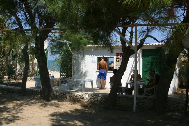 Persone sedute vicino a una casetta bianca tra gli alberi.