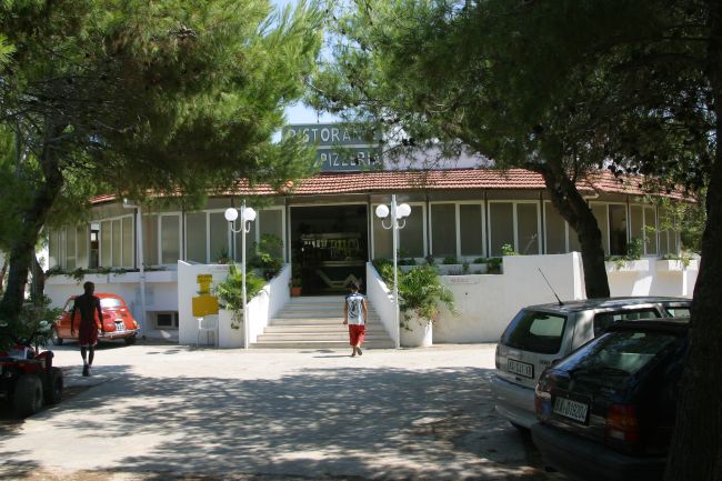 Entrata di un ristorante pizzeria circondato da alberi.