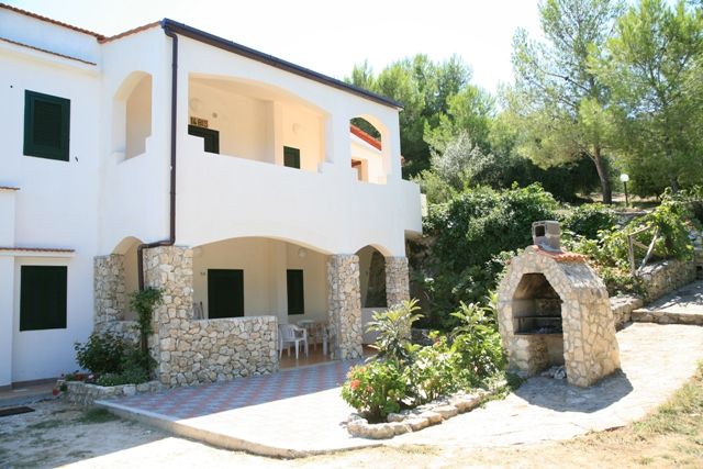 Villa bianca con portico e forno a legna esterno.