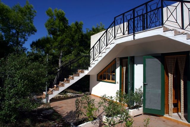 Casa bianca con terrazza e scala esterna.