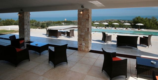 Area relax coperta con vista su piscina e mare.