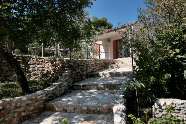 Sentiero lastricato circondato da alberi porta a una casa in pietra.