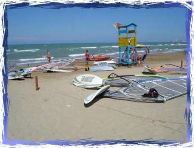 Spiaggia con attrezzature da windsurf e torretta colorata.