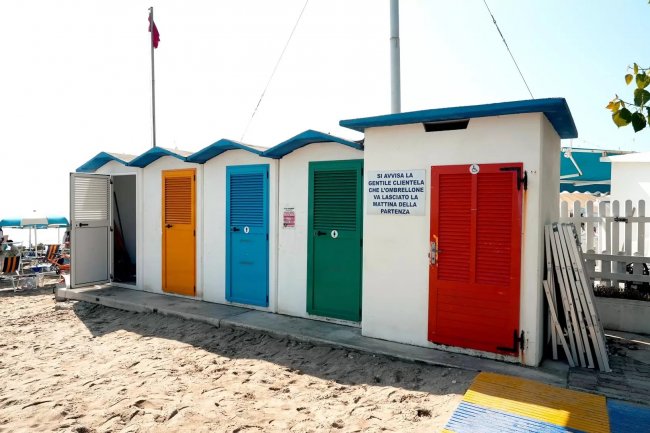 Cabine colorate sulla spiaggia sabbiosa.