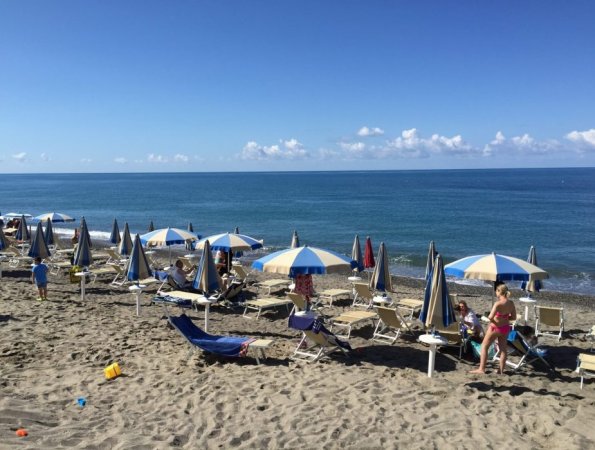 Spiaggia con ombrelloni a righe bianche e blu.