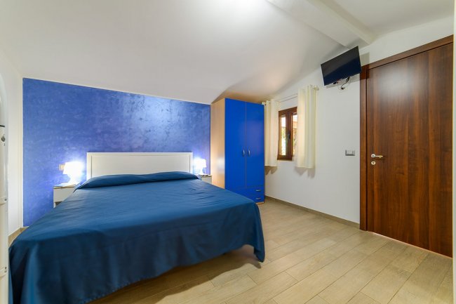 Camera con letto matrimoniale e parete blu.