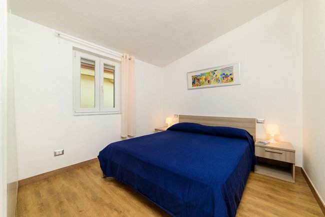 Camera da letto con letto matrimoniale blu e dipinto colorato.