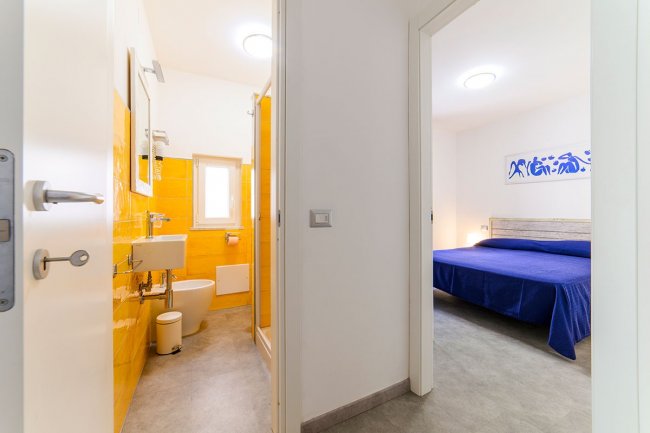 Bagno giallo e camera da letto con letto blu.