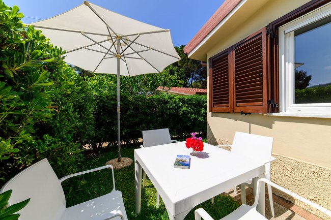 Tavolo bianco con ombrellone nel giardino.