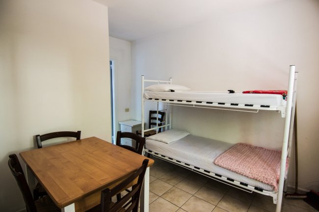 Letto a castello e tavolo con sedie in una stanza.