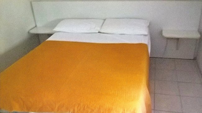 Letto matrimoniale con copriletto arancione.