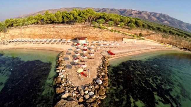 Veduta aerea di una spiaggia con ombrelloni e pietra frangiflutti.