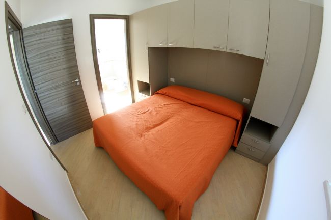 Camera con letto matrimoniale e armadio beige.