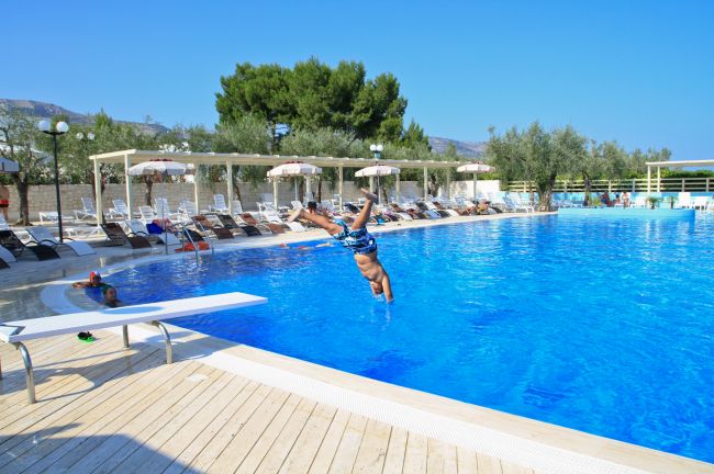Persona tuffa in piscina blu.