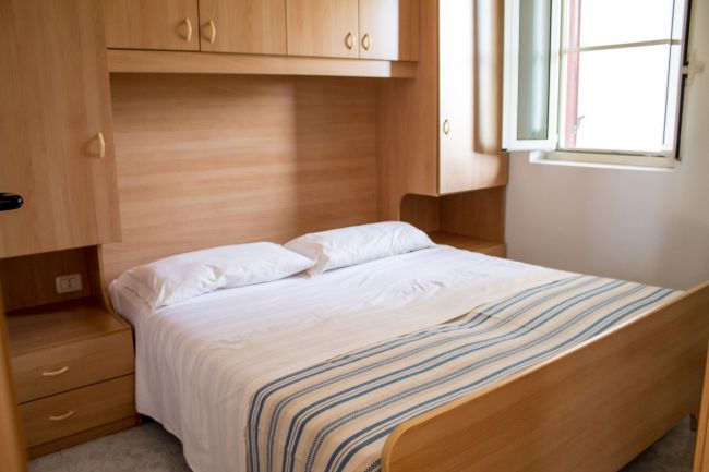 Camera da letto con letto matrimoniale e armadi in legno chiaro.