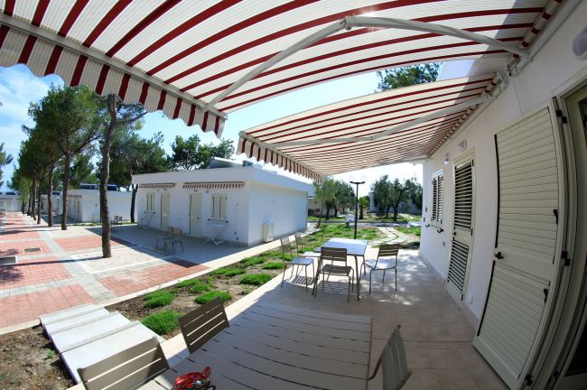 Terrazza esterna con tende a strisce e tavolo da pranzo.