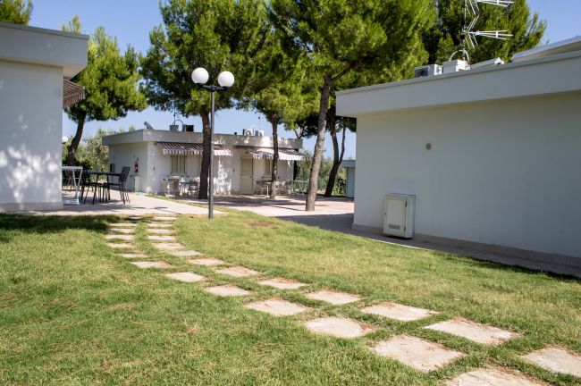 Giardino con vialetto in pietra e edifici bianchi.